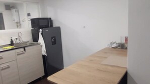 Eine kleine Küche mit einem Holztisch, einem schwarzen Kühlschrank und einer Mikrowelle.