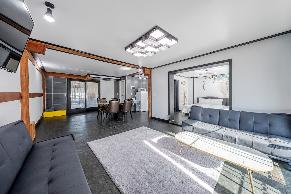 A modern living room with a sofa, a coffee table, and a dining area with chairs and a table.