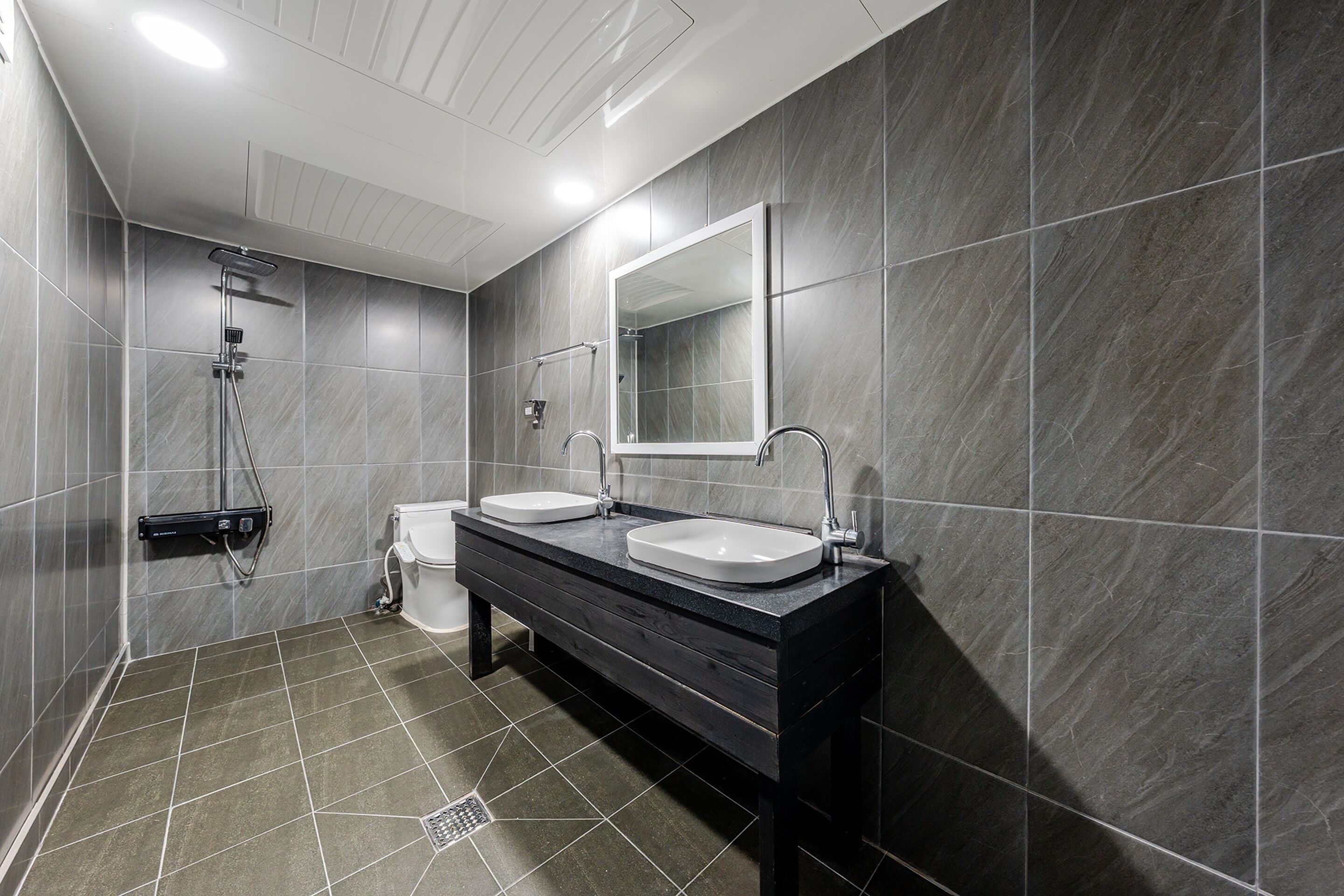 Une salle de bain moderne avec deux lavabos, un grand miroir et une douche.
