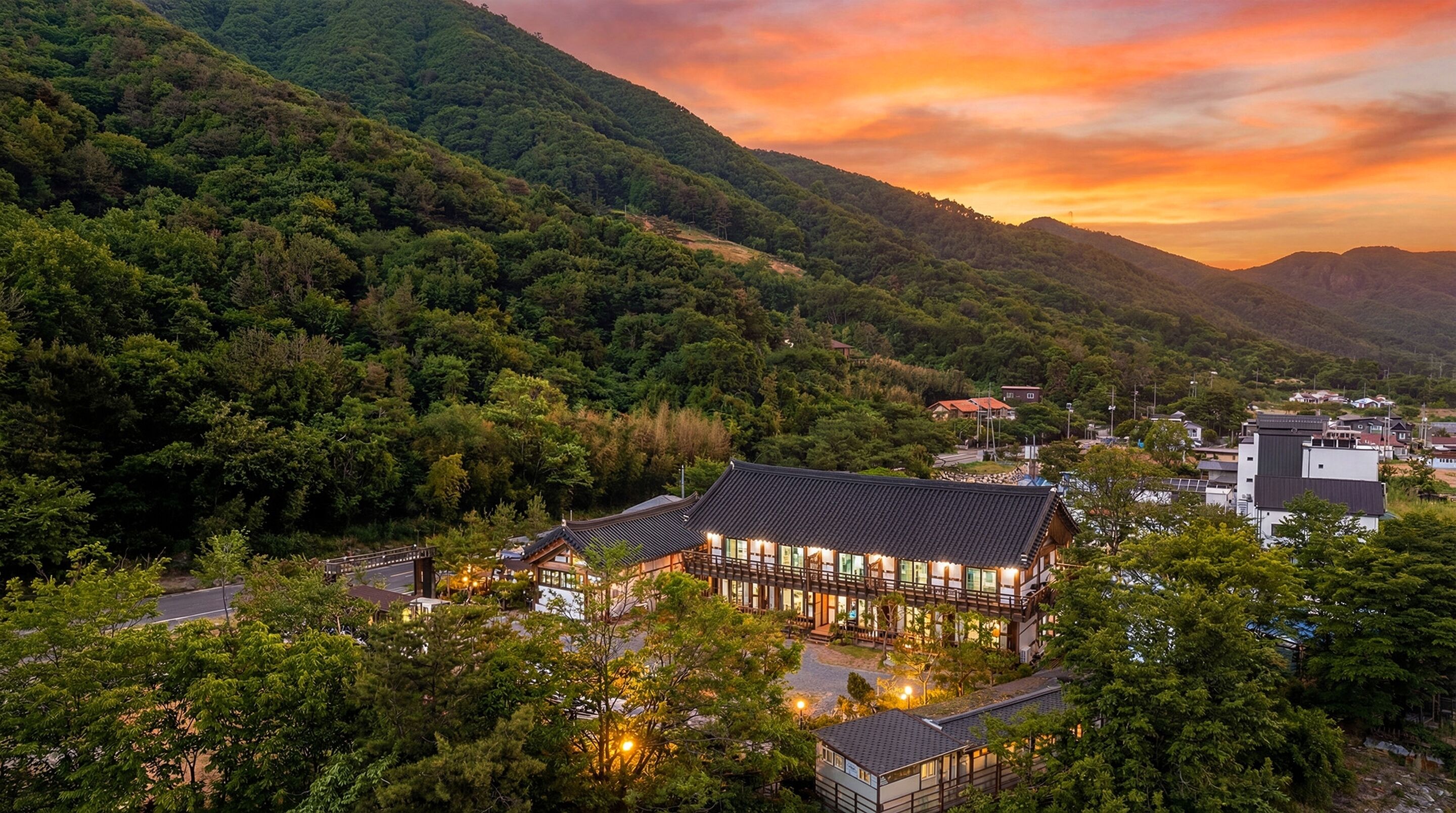 A traditional Japanese-style building with a tiled roof, surrounded by lush greenery and mountains in the background.