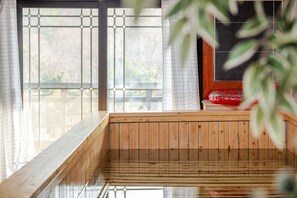 A wooden sauna with a bench and a red object on a table. - Gyeongju Palace Hanok Kids Pool Villa (Gyeongju)