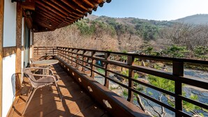 A wooden balcony with a table and chairs, overlooking a mountainous landscape. - Gyeongju Palace Hanok Kids Pool Villa (Gyeongju)