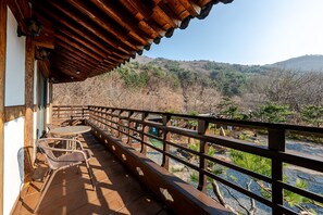 Un balcon en bois, agrémenté d’une table et de chaises, qui offre une vue sur un paysage montagneux.