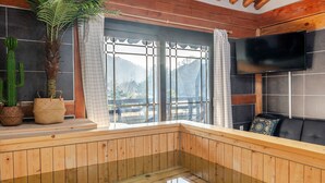A wooden sauna with a glass floor, a large window with a view of mountains, a television on the wall, and a cactus plant. - Gyeongju Palace Hanok Kids Pool Villa (Gyeongju)