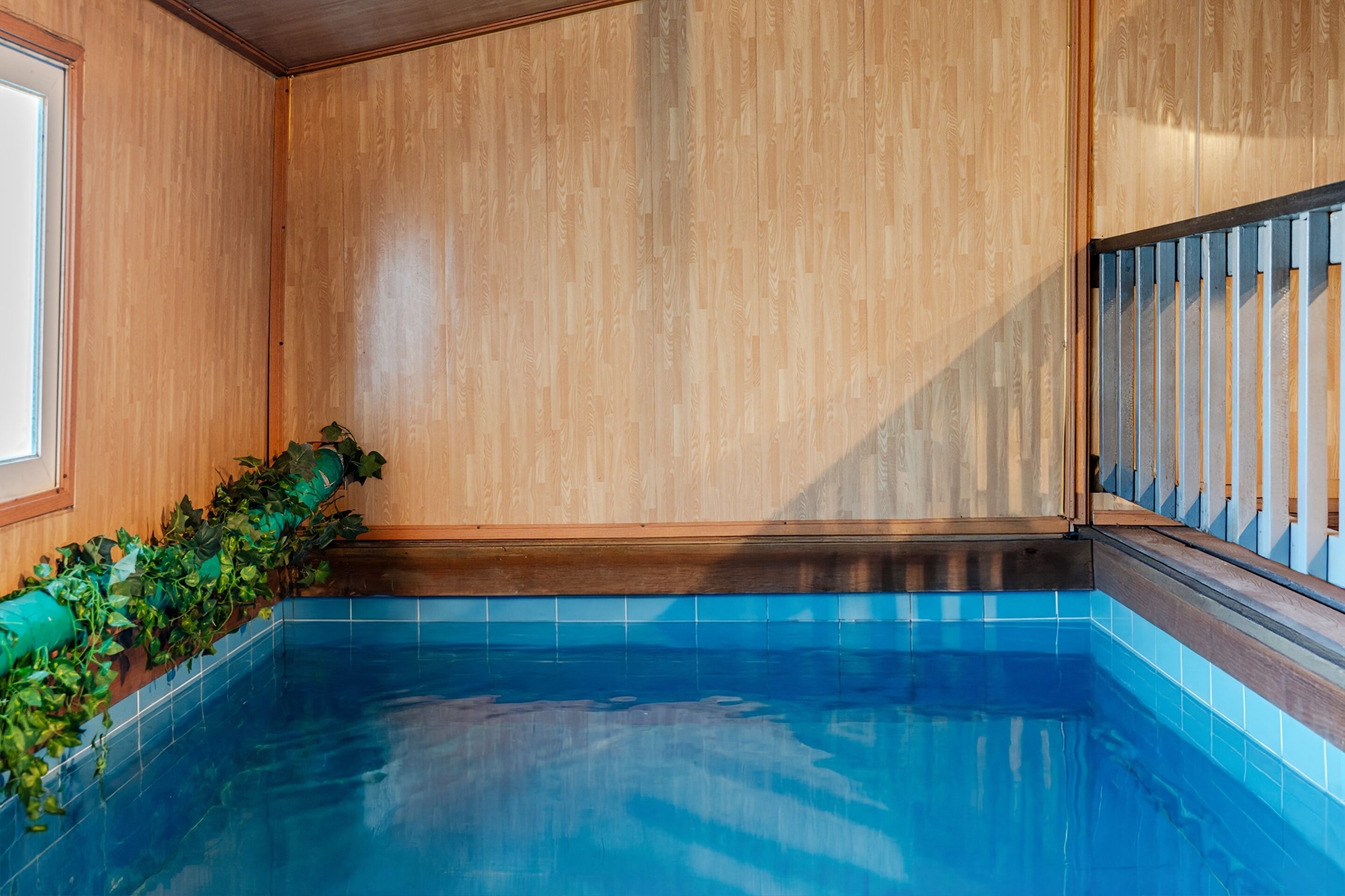 A swimming pool with wooden walls and a blue tiled floor.