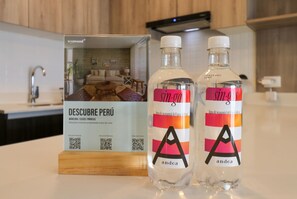 Two bottles of 'sin.g' water with a wooden box labeled 'DESCUBRE PERÚ' in a kitchen setting. - w* | Engaging 2BR in the Heart of Barranco (Barranco)