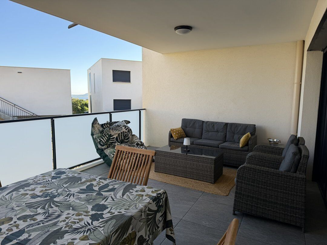 A balcony with a bed, a sofa, and a chair.