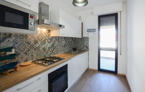 A compact kitchen with a gas stove, microwave, and modern cabinetry. - Cozy apartment in Viareggio with WiFi (Viareggio)