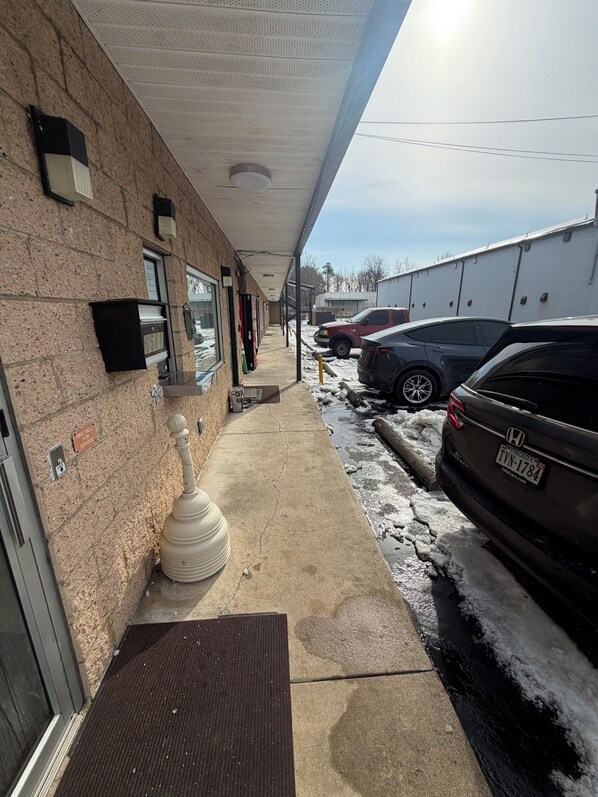 A building exterior with a parking area, a mailbox, and a snow-covered ground.