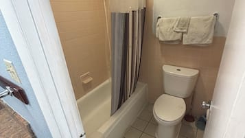 Un baño con bañera, inodoro y cortina de ducha.