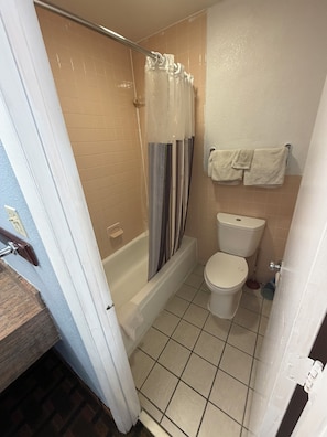 A bathroom with a bathtub, toilet, and a shower curtain. - TRAVEL INN (Richmond)
