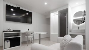 A modern hotel room with a flat-screen TV, a small dining table, a sofa, and a compact kitchenette. - Bucheon Songnae Number 25 (Bucheon)