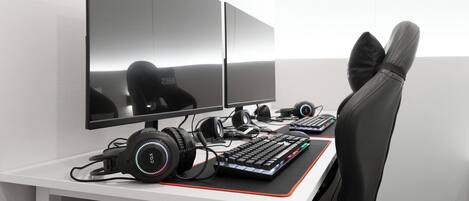 A gaming setup with two monitors, a keyboard, headphones, and a gaming chair.