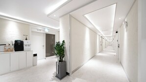 A modern hotel corridor with a self-service kiosk, a reception area, and a plant. - Bucheon Songnae Number 25 (Bucheon)
