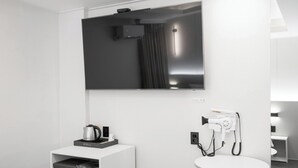 A modern bathroom with a large mirror, a mounted TV, a hairdryer, and a coffee maker on a shelf. - Bucheon Songnae Number 25  (Bucheon)