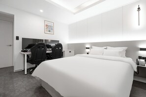 Une chambre d’hôtel moderne, dotée d’un grand lit, d’un bureau avec une chaise, d’un téléphone et d’un tableau encadré au mur.