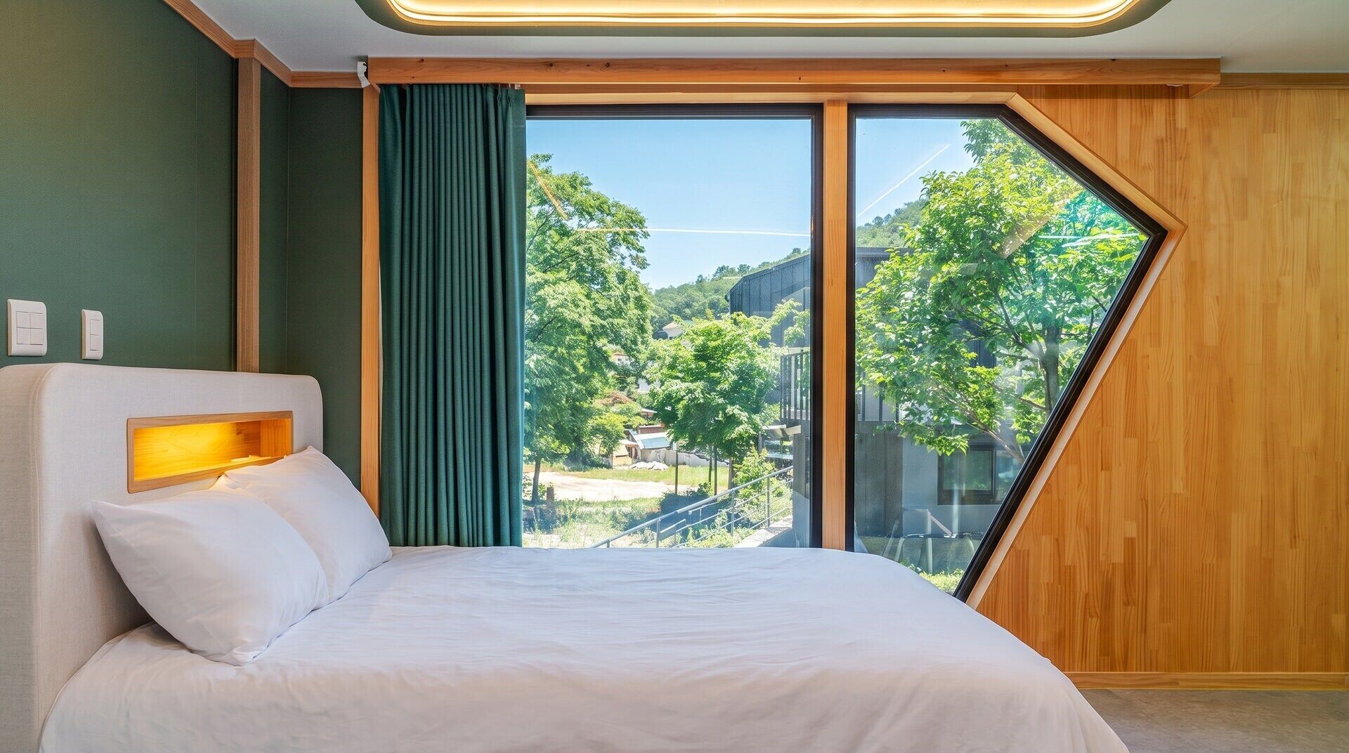 Ett modernt hotellrum med en stor säng, utsikt över omgivningarna och en vägg med träpanel som ger rummet karaktär.