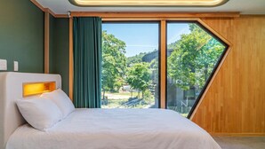 Ein modernes Hotelzimmer mit einem großen Bett, Blick ins Freie und einer Wand mit Holzpaneelen.