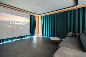 Un salon moderne doté d’un grand écran diffusant des contenus « essentiels », et d’un coin salon confortable.