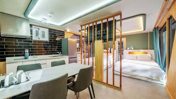 Une chambre d’hôtel moderne équipée d’une kitchenette, d’un coin repas et d’un lit.