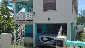 Une maison à deux étages avec un balcon, un garage et une entrée fermée par un portail.