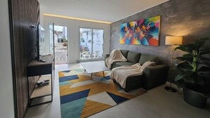 A modern living room with a sofa, coffee table, and a colorful abstract painting on the wall. - Vista Mar house & Studio (Ponta Delgada)