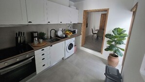 A compact kitchen with white cabinets, a washing machine, and a sink. - Vista Mar house & Studio (Ponta Delgada)