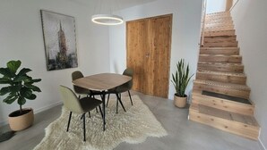 A dining area with a wooden table, chairs, a fluffy rug, and a staircase. - Vista Mar house & Studio (Ponta Delgada)