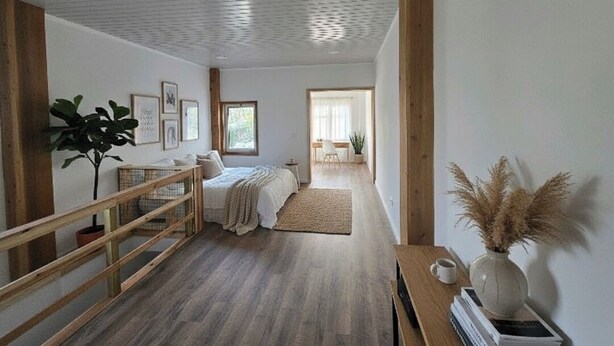 A spacious bedroom with a wooden floor, a bed, a desk, and a window. - Vista Mar house & Studio (Ponta Delgada)