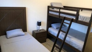 Una camera con un letto a castello, un comodino e una lampada.