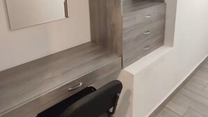 Una camera moderna con scrivania integrata, una sedia e un armadio con ripiani aperti.