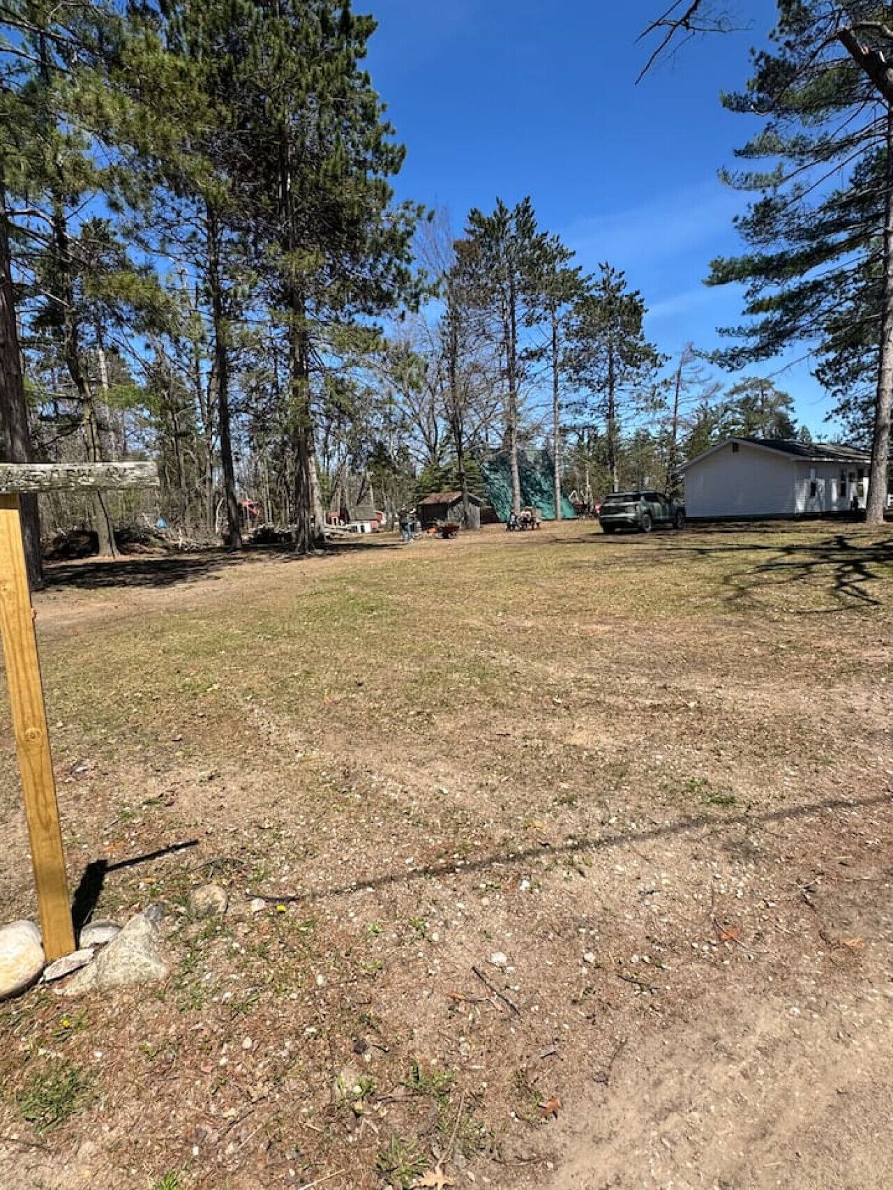 A fenced yard with a wooden post, a small shed, and a white building.