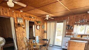 L’intérieur d’un chalet chaleureux, comprenant un coin repas, une cuisine et un grand tapis.