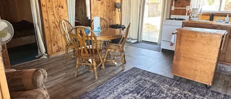 Interior acogedor de una cabaña con comedor, cocina y una alfombra grande.