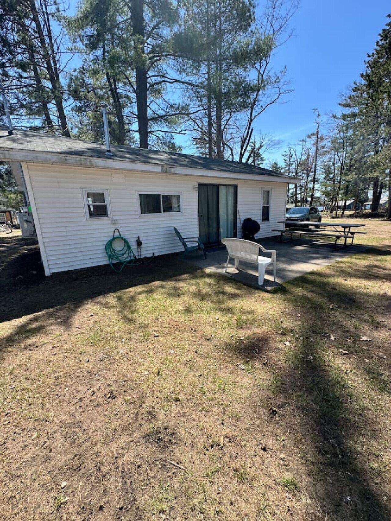 Une petite maison mobile dotée d’un patio couvert, d’un tuyau d’arrosage et d’une table de pique-nique.