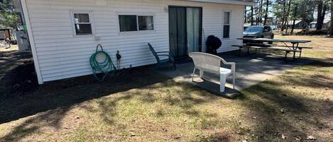 Une petite maison mobile dotée d’un patio couvert, d’un tuyau d’arrosage et d’une table de pique-nique.