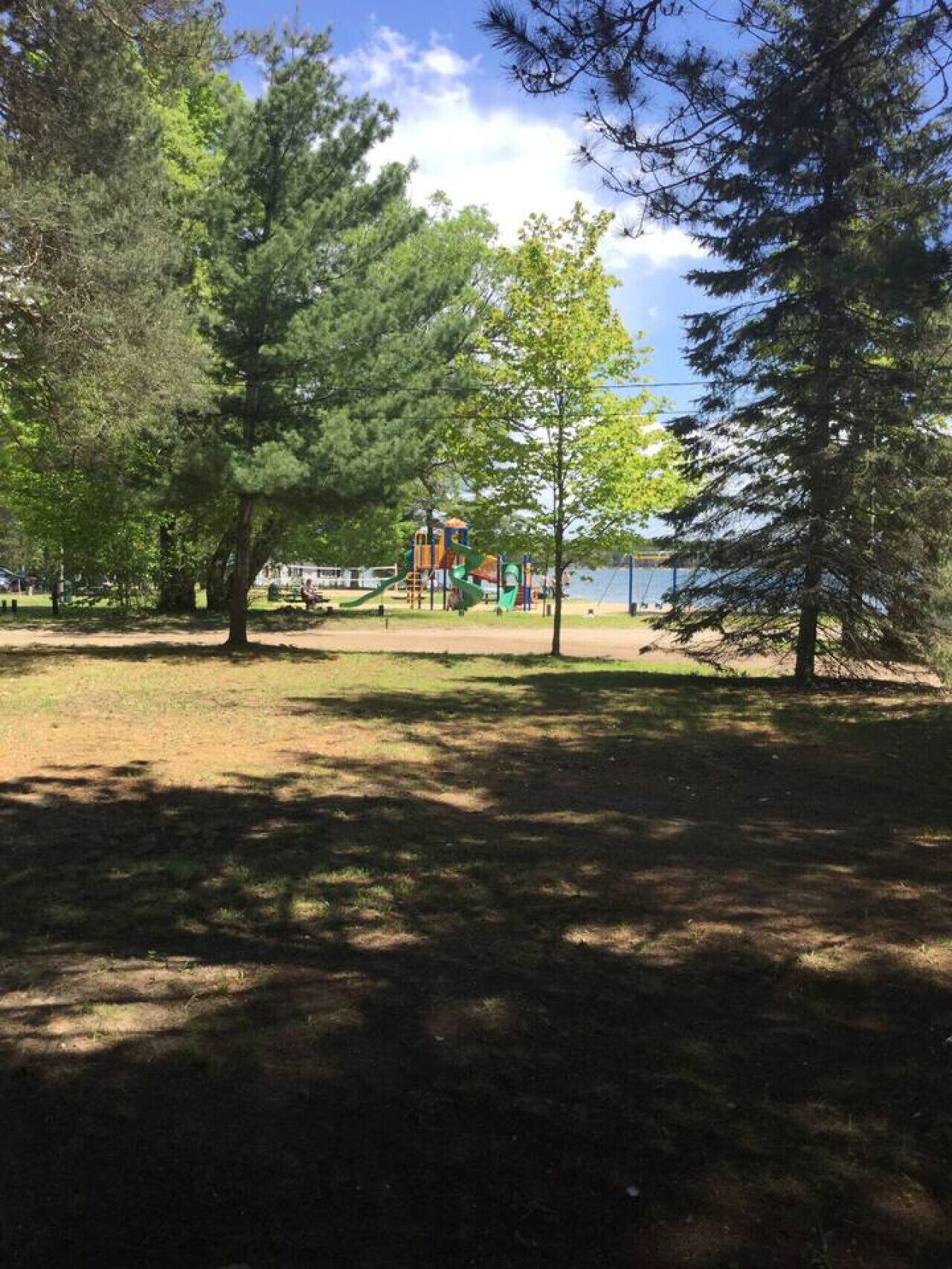 A park with a playground and a lake in the background.