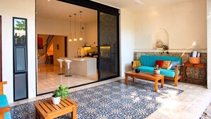 A spacious living area with a large sliding glass door leading to a kitchen and dining area, a blue patterned floor, and a ceiling fan. - Tropical Paradise in Centro Historico of Merida (Merida)