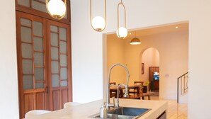 A modern kitchen with a central island, a built-in sink, and pendant lighting. - Tropical Paradise in Centro Historico of Merida (Merida)