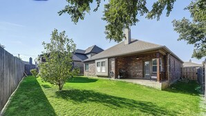 Een woonhuis met een bakstenen gevel, een overdekte veranda en een verzorgd gazon.