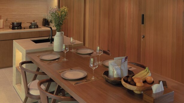 A modern kitchen with wooden cabinetry, a central island with a vase of flowers, and pendant lighting. - The Akasha Berawa Luxury Villas (Tibubeneng)