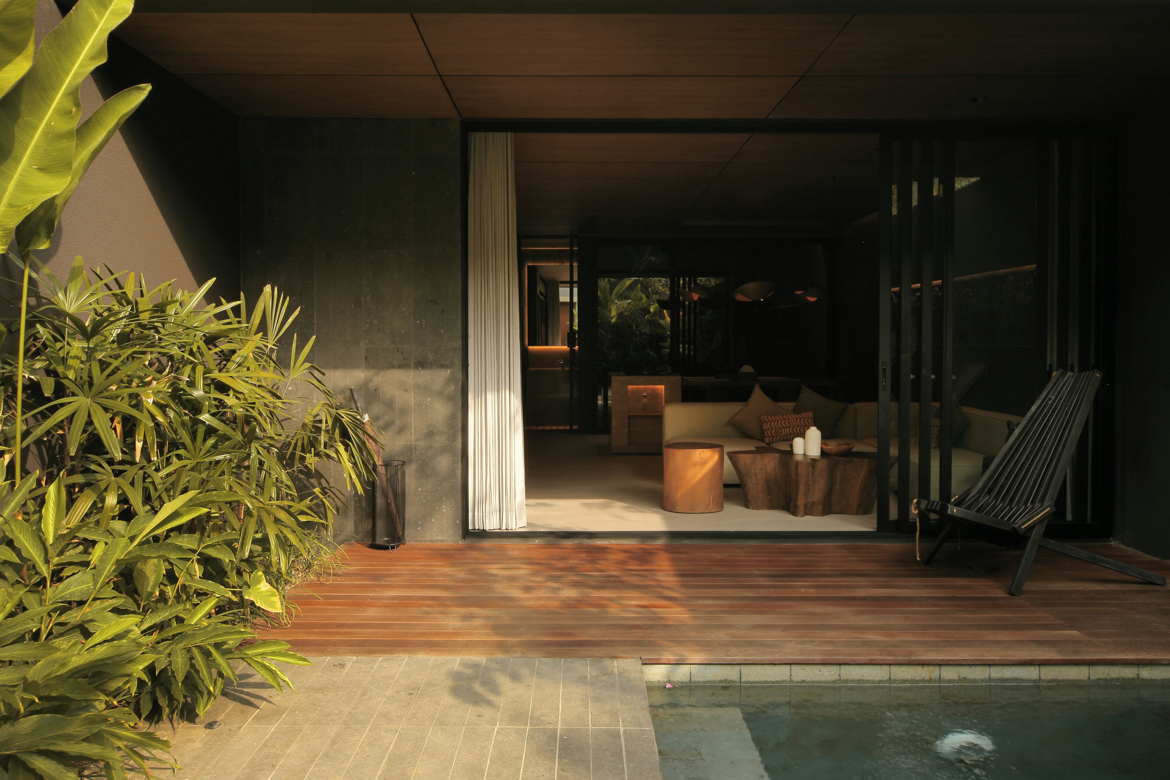 A modern outdoor living area with a pool, wooden flooring, and a seating arrangement.