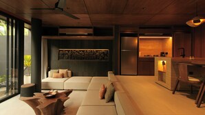 A modern living room with a sofa, coffee table, and a dining area with a bar. - The Akasha Berawa Luxury Villas (Tibubeneng)