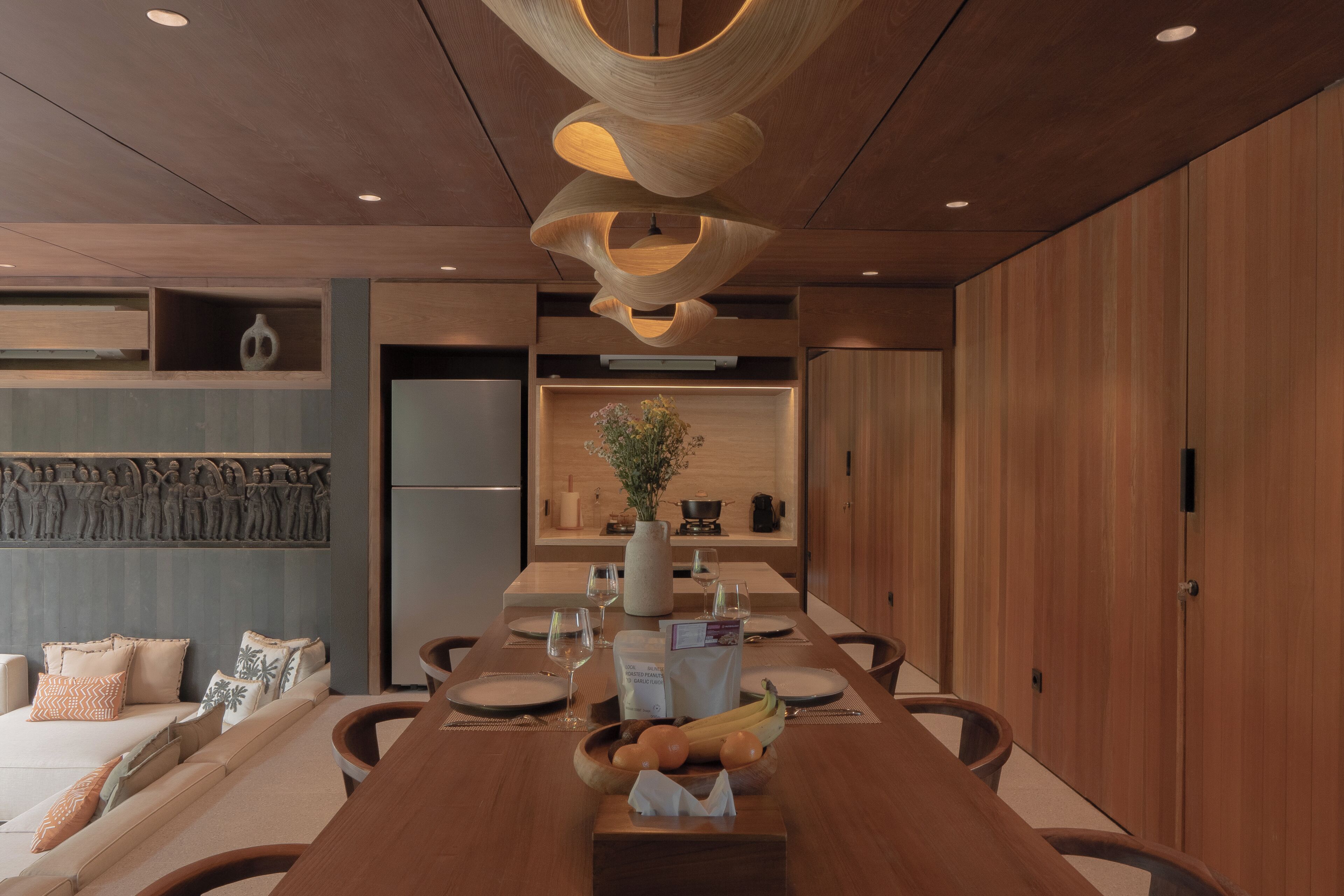 A modern dining area with a wooden table, chairs, and a unique ceiling light fixture.