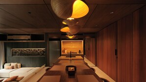 A modern interior with a long dining table, wooden flooring, and a kitchen area with a built-in oven. - The Akasha Berawa Luxury Villas (Tibubeneng)
