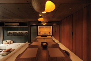 A modern interior with a long dining table, wooden flooring, and a kitchen area with a built-in oven. - The Akasha Berawa Luxury Villas (Tibubeneng)