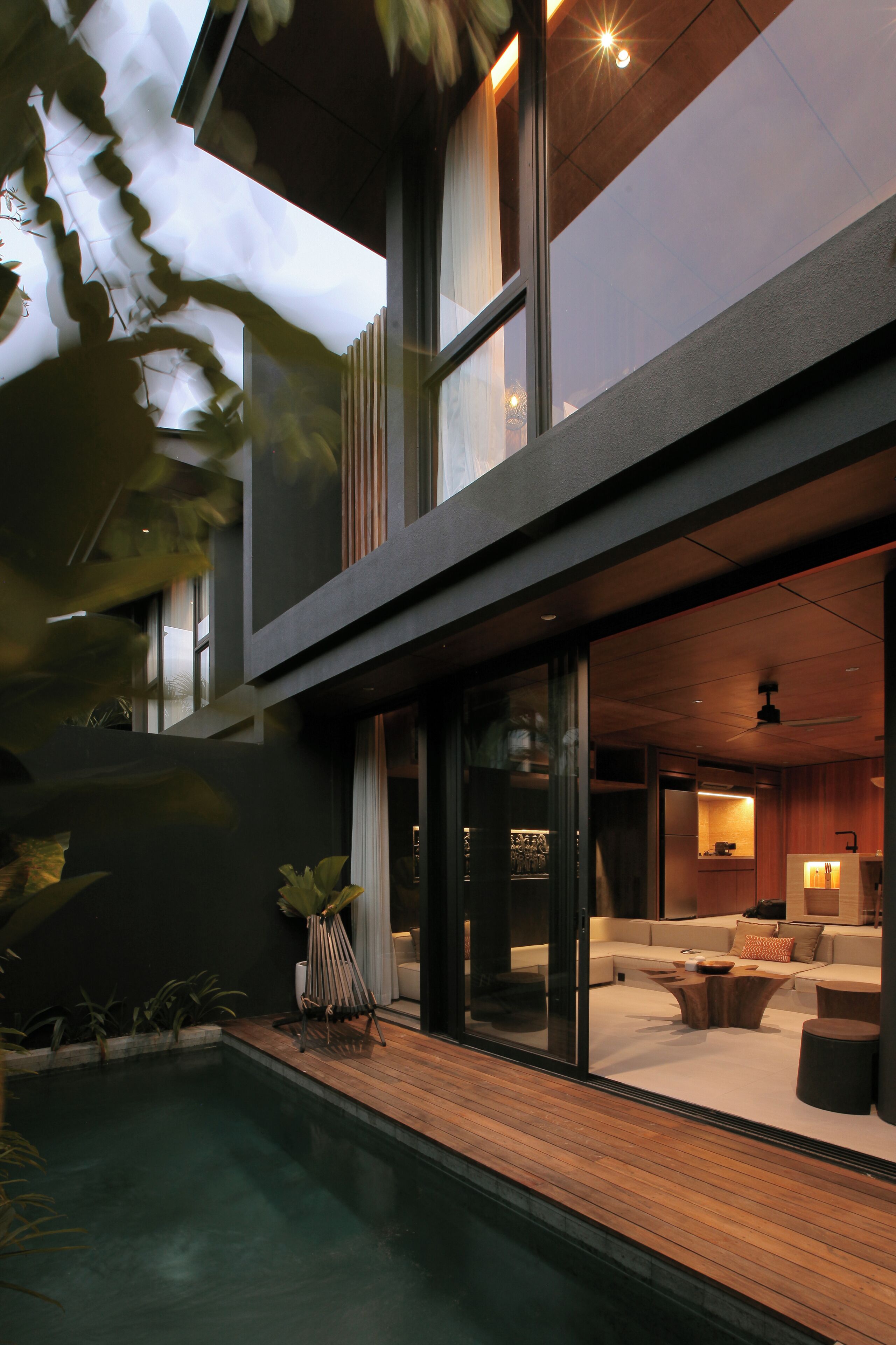 Una moderna casa a due piani con piscina, un soggiorno vetrato e una cucina a vista.