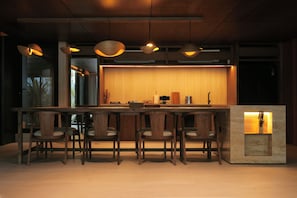 Cozinha moderna com ilha central, banquetas, iluminação pendente e bancada embutida.