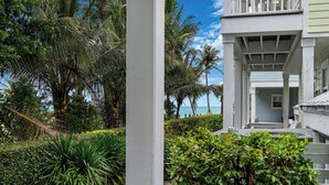 A coastal building with a balcony overlooking the sea, surrounded by lush greenery and palm trees. - OCEAN VIEW ANGLERS REEF - POOL, BEACH. Walk or bike to local food + bars (Islamorada)