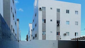 Un espace piscine aménagé sur le toit, comprenant deux piscines rectangulaires et une piscine circulaire, le tout entouré d’un immeuble d’appartements moderne.